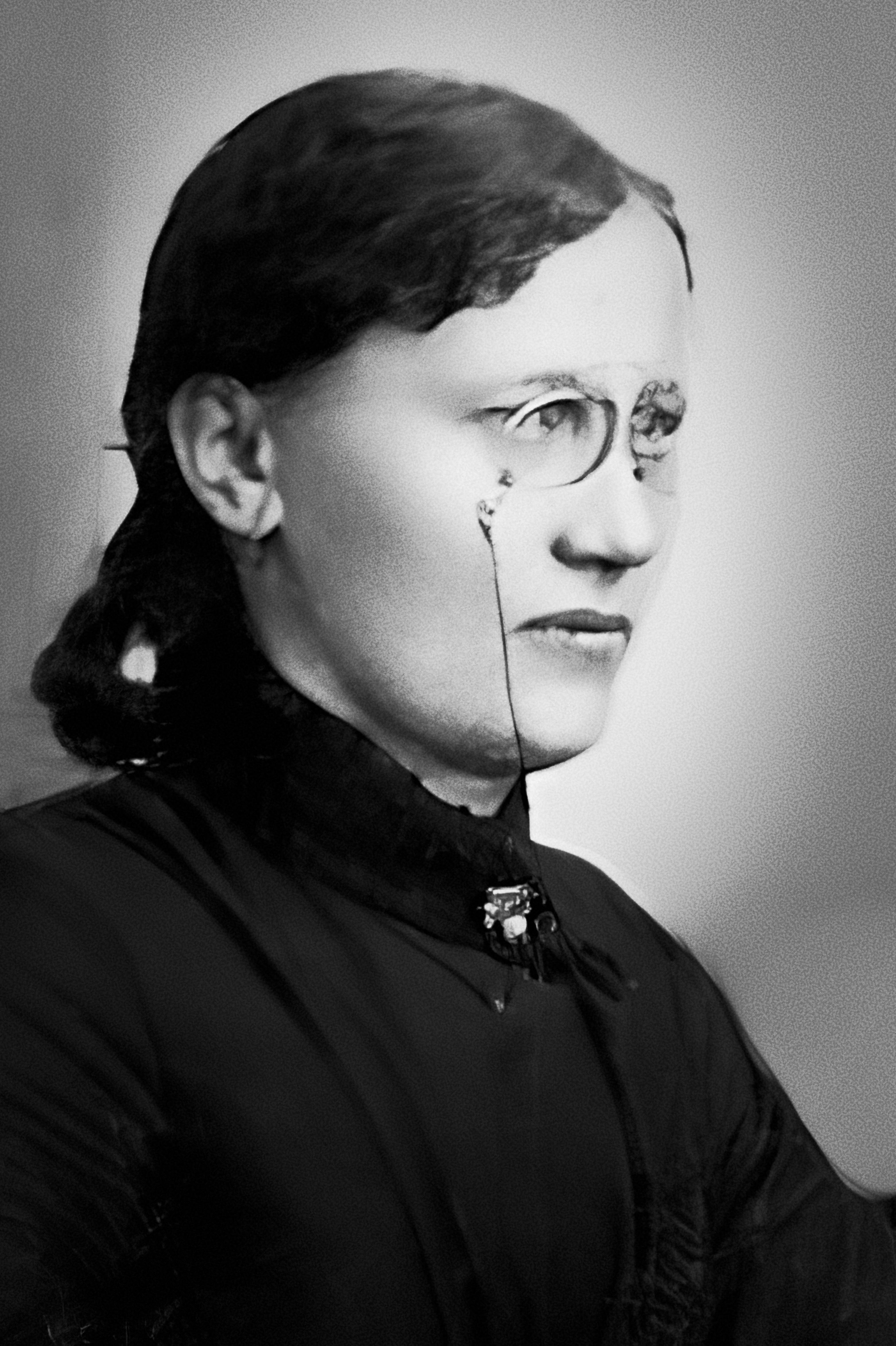 A black-and-white photograph of a woman wearing pince-nez glasses