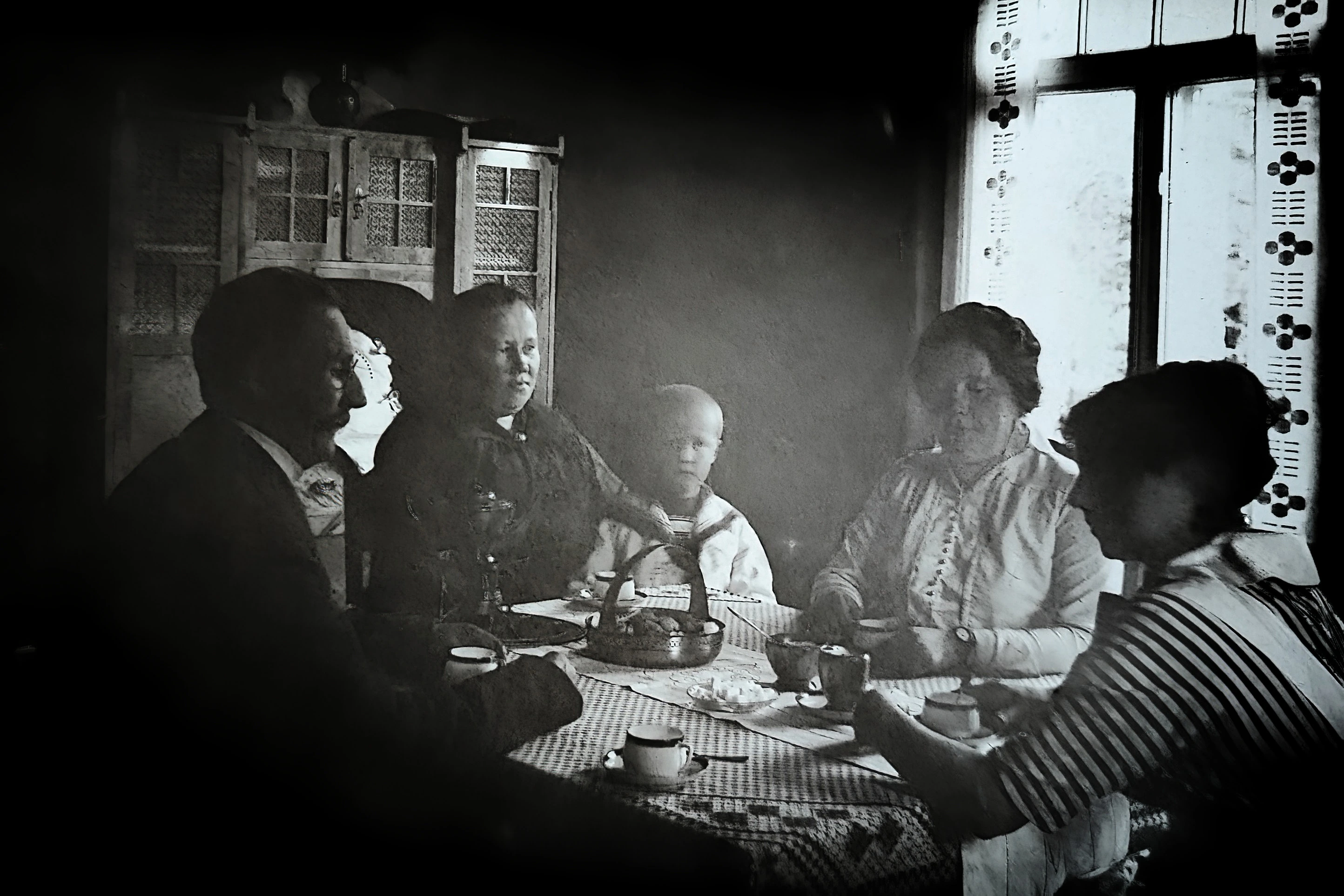 Old black-and-white photograph of a four adults a young boy around a coffee table