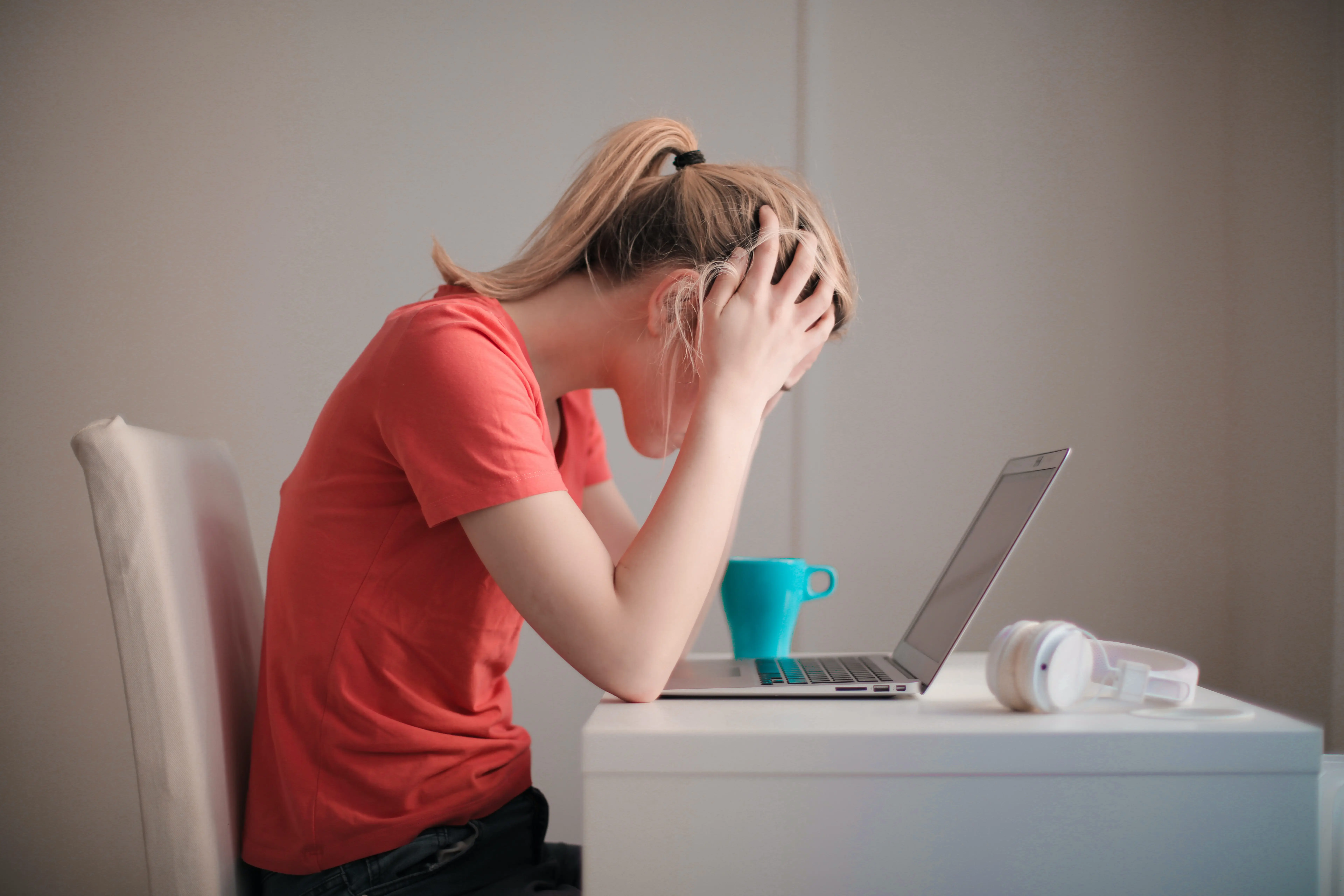 A young woman in a red T-shirt looking at her laptop